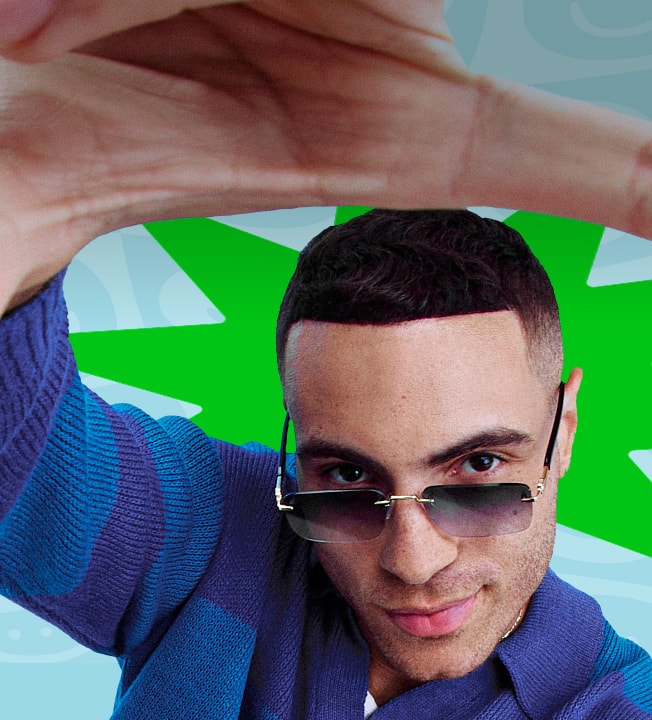Man in Zenni sunglasses and blue-striped sweater holding his hand up playfully, framing the view.